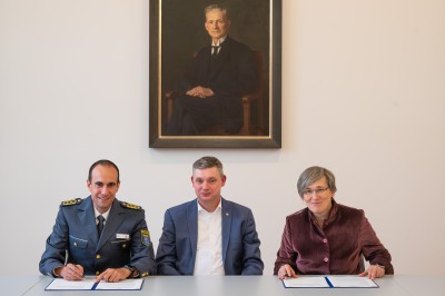 Unter den Augen des Gie&szlig;ener Kirchenhistorikers und NS-Regime-Kritikers Gustav Kr&uuml;ger: Unterzeichnung der Kooperationsvereinbarung f&uuml;r die &bdquo;Allianz f&uuml;r Demokratie&ldquo;, die die vertrauensvolle Zusammenarbeit zwischen dem Polizeipr&auml;sidium Mittelhessen und der Arbeitsstelle Holocaustliteratur der JLU besiegelt. V.l.n.r.: Polizeipr&auml;sident Torsten Kr&uuml;ckemeier, AHL-Leiter Prof. Dr. Sascha Feuchert, JLU-Pr&auml;sidentin Prof. Dr. Katharina Lorenz. Foto: JLU / Roland Duss